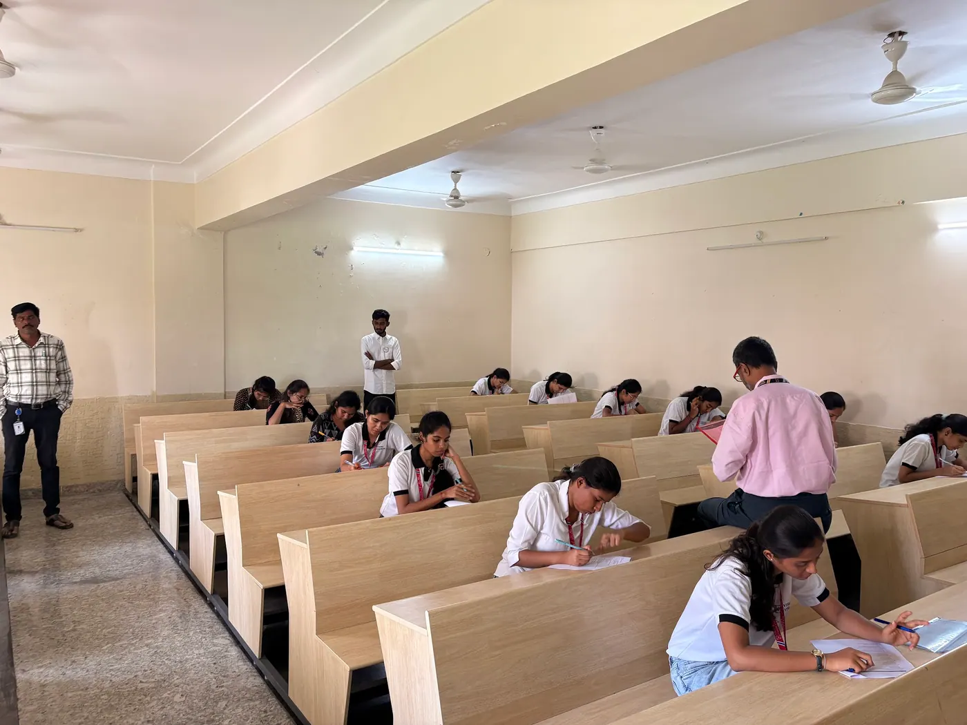 Invigilators walking the rows as students write the assessment