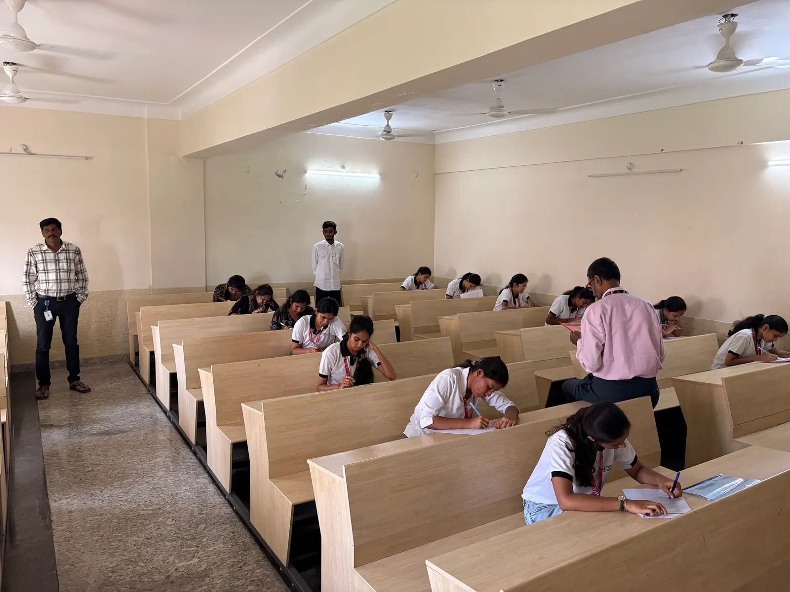 Students writing the assessment at long desks in an exam hall