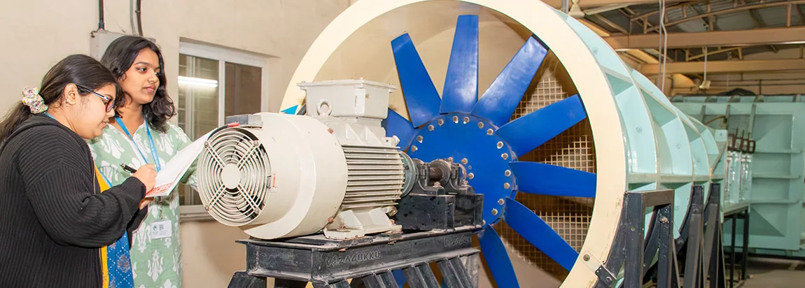 Students examining a large axial fan rig in a mechanical engineering lab