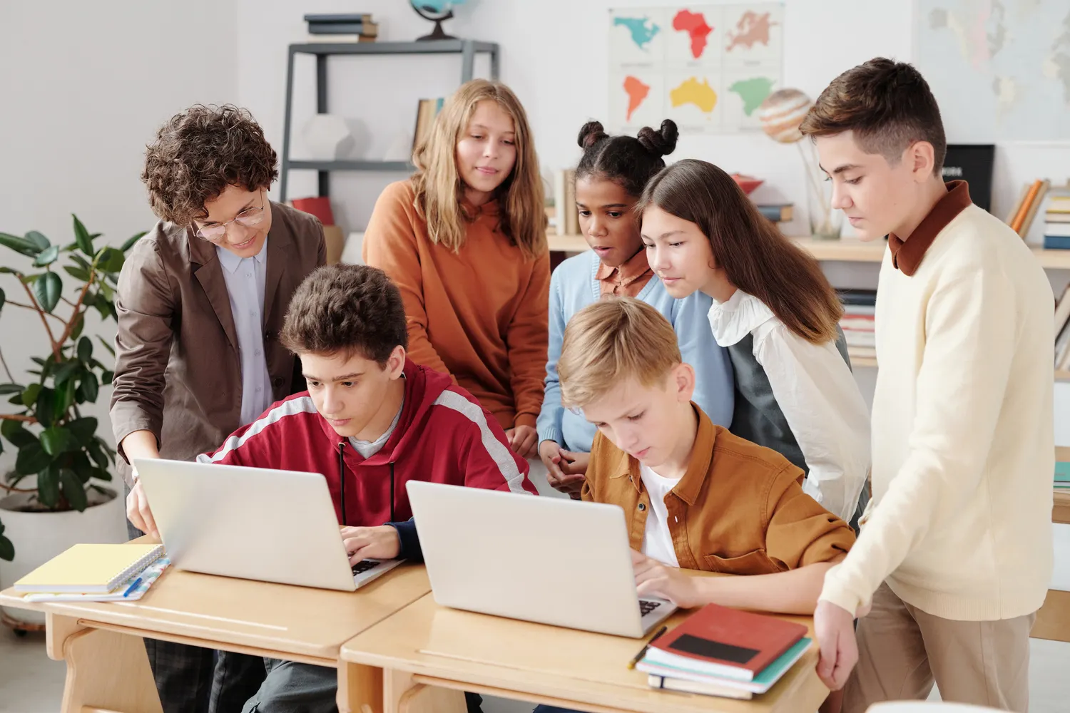 Pupils collaborating around laptops in a classroom