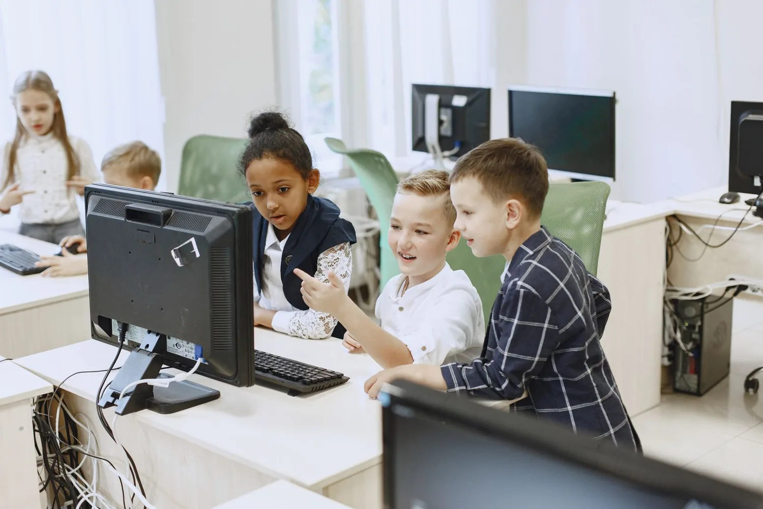 Pupils working together at desktop computers in a classroom