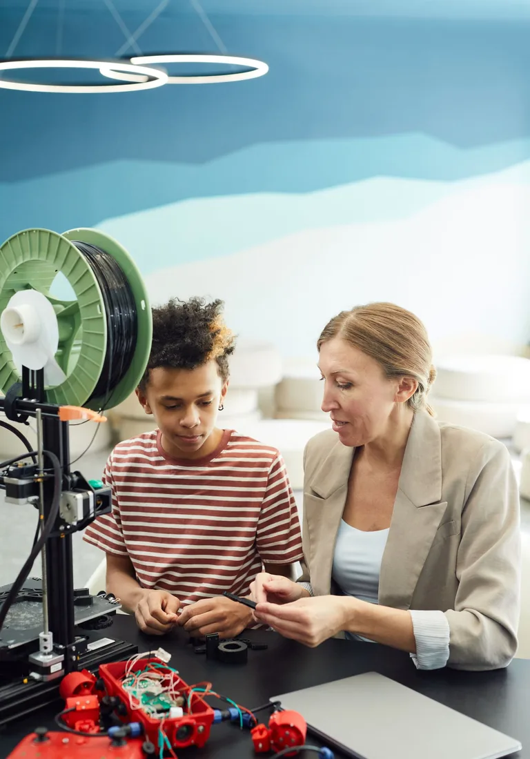 A mentor helps a pupil with a 3D printing project