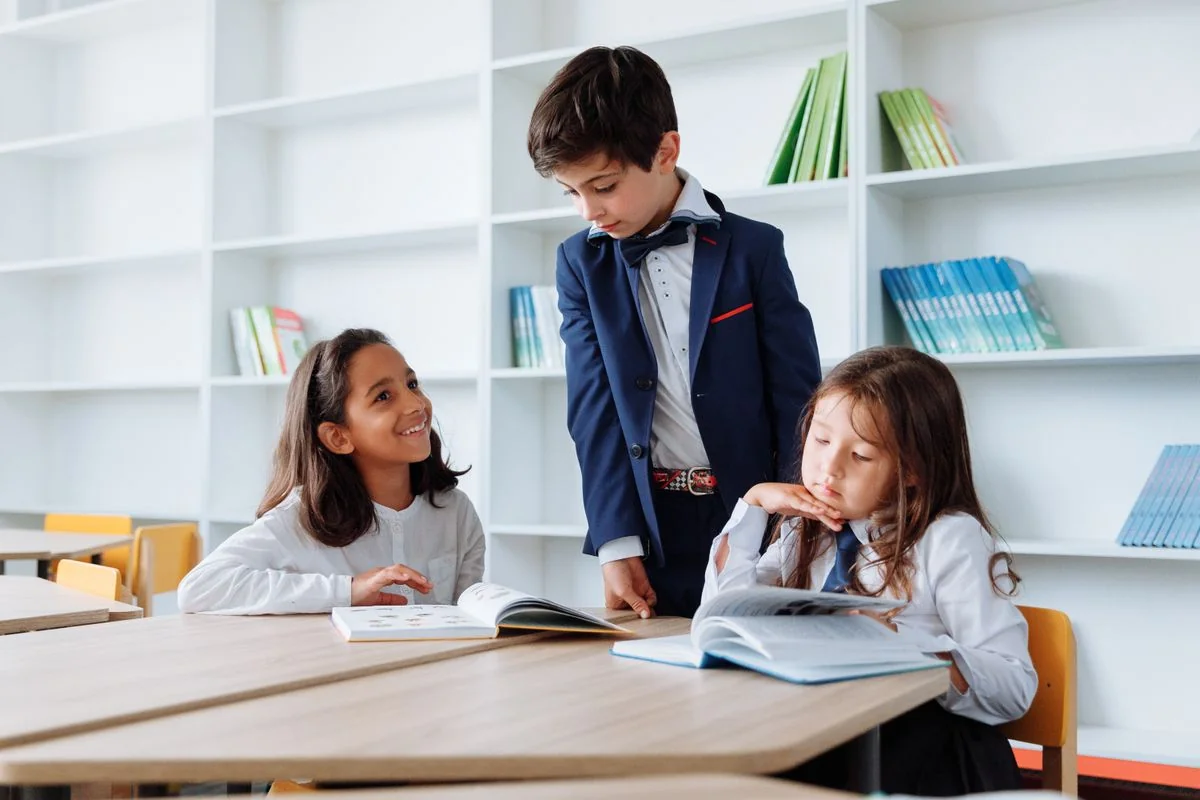 Three school students reading together at a library table