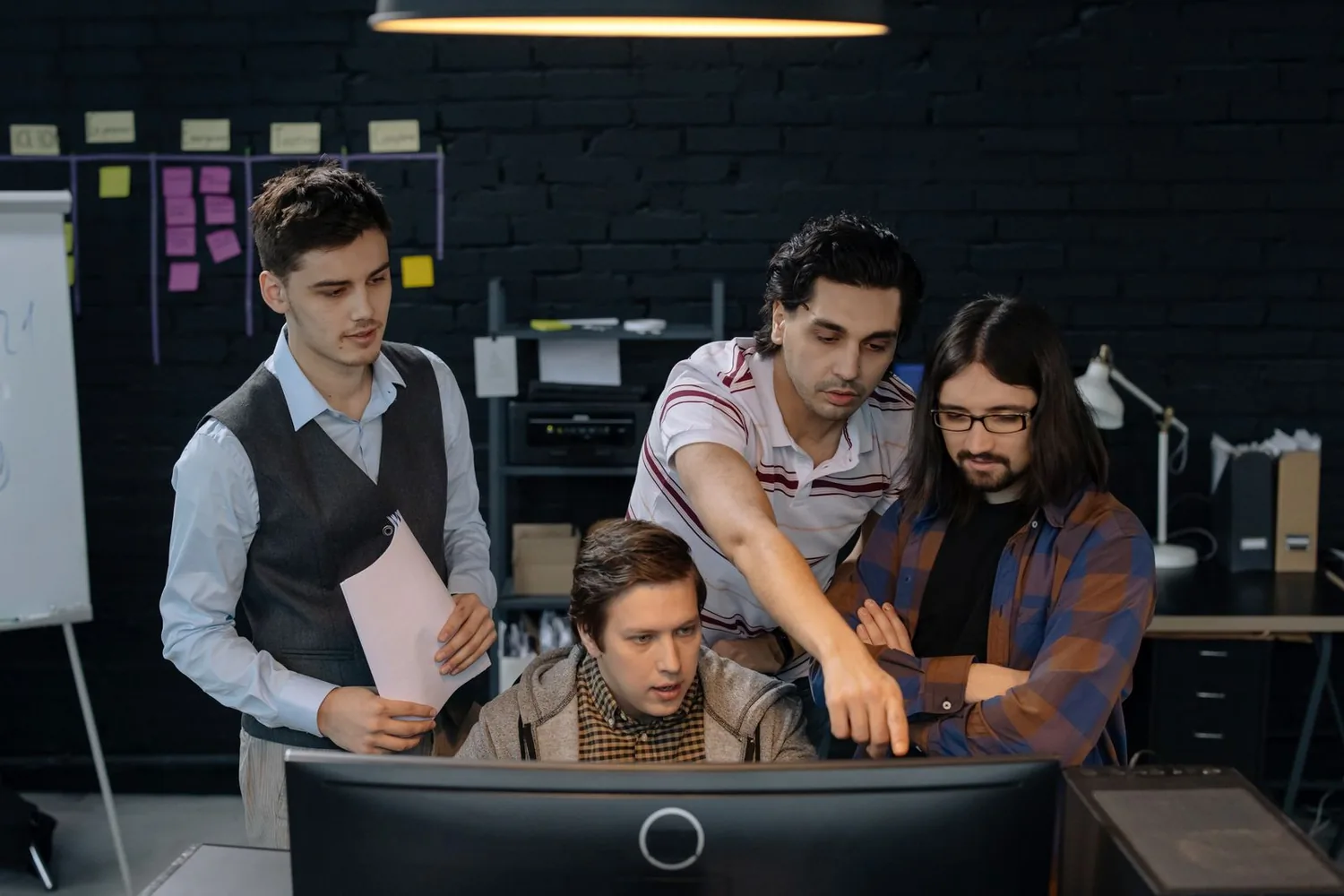 Team discussing a problem around a computer